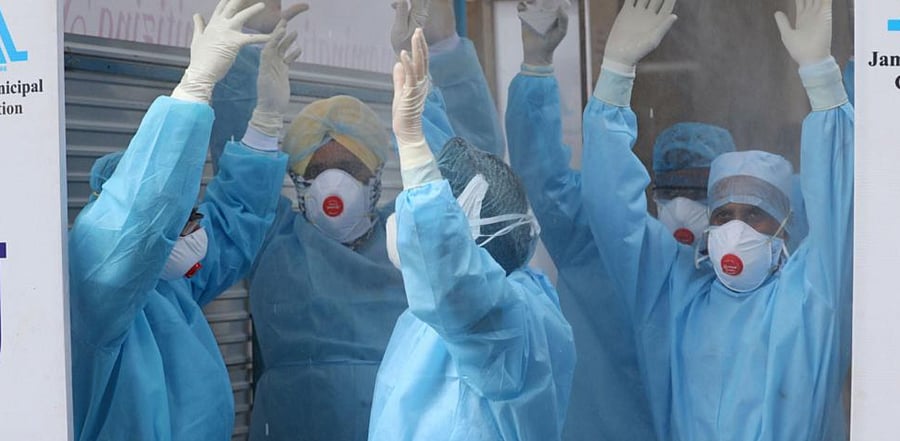 Paramedical staff members are seen inside a full body sanitizing machine outside Government Medical College. Credit: PTI Photo