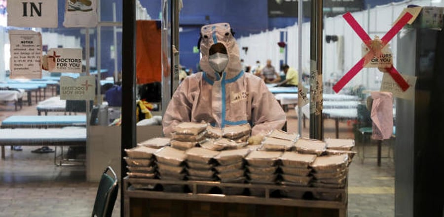 A medical health worker personal protective equipment (PPE) collects food boxes from a cart inside a quarantine centre for the coronavirus disease (COVID-19) patients. Credit: Reuters Photo