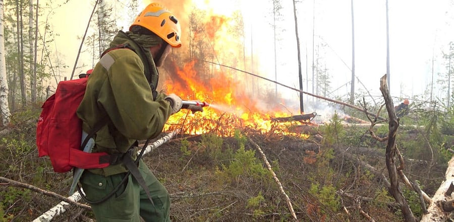 A specialist sprays water while extinguishing a forest fire in Krasnoyarsk region, Russia. Credit: Reuters