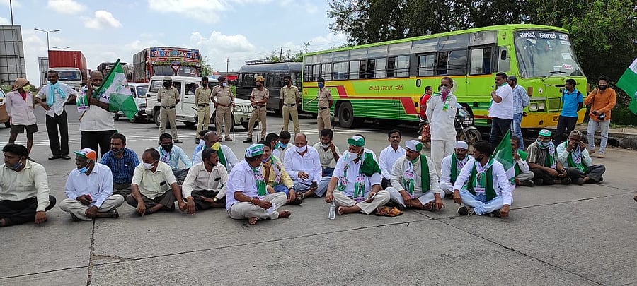 Congress-Janata Dal (Secular) workers staging sit-in protest by blocking the Pune-Bengaluru national highway near toll plaza at Hirebagewadi village in Belagavi taluk on Monday. Credit: DH Photo