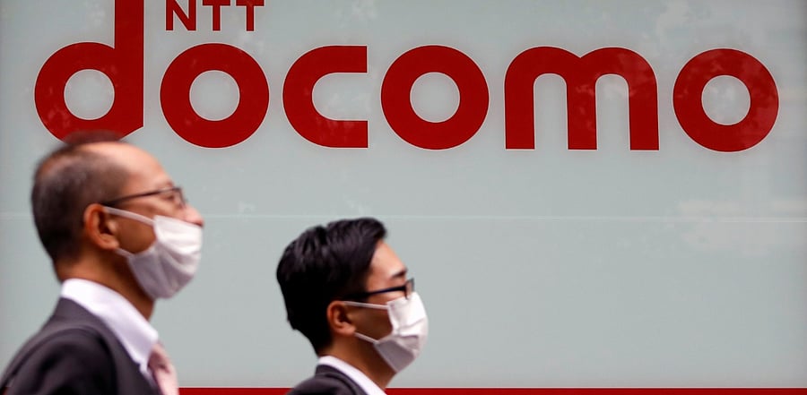 Passersby wearing protective face masks walk past in front of NTT Docomo shop in Tokyo, Japan. Credit: Reuters Photo