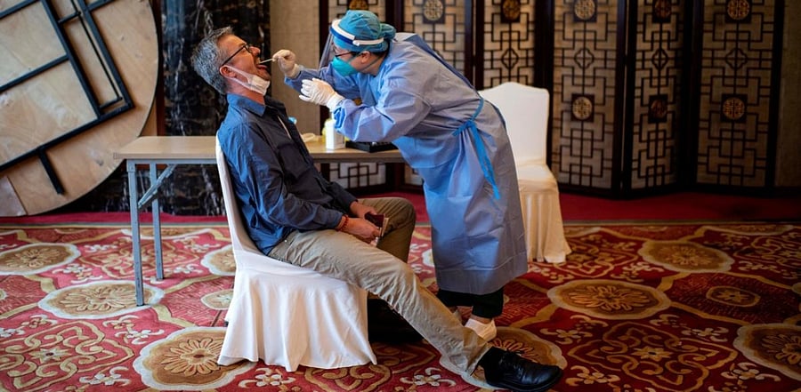 A worker in a protective suit takes a swab from a journalist to test for Covid-19. Credit: AFP