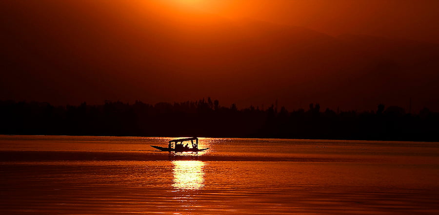 A man rows a boat during sunset at Dal lake in Srinagar. Credit: AFP Photo