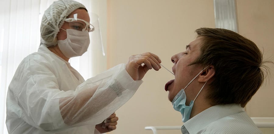 A health worker wearing protective gear takes a swab from a man to test for the coronavirus disease  at clinic in Moscow, Russia  Credit: Reuters Photo