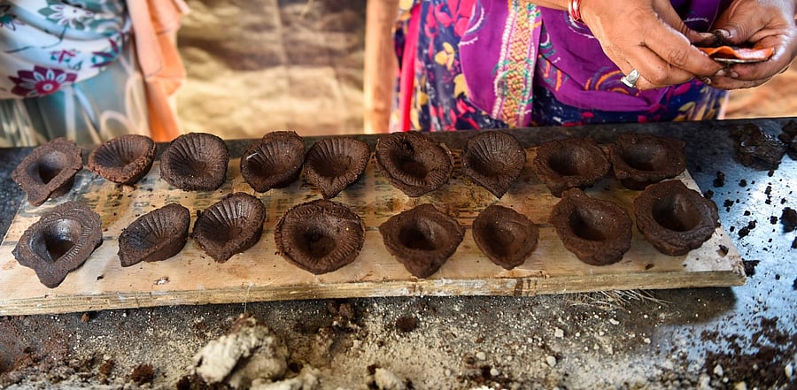Women make oil lamps or 'diyas' with a mix of cowdung and mud ahead of the Diwali festival. Credit: AFP Photo