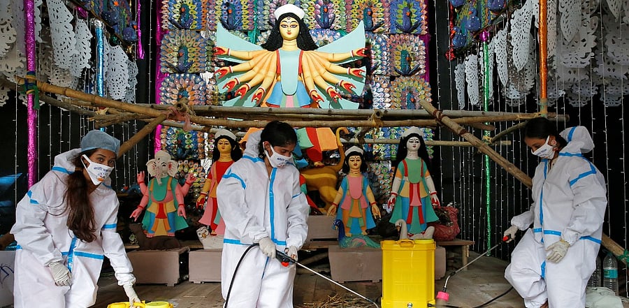 Women wearing personal protective equipment (PPE) sanitize a "pandal" or a temporary platform, ahead of Durga Puja festival, amidst the spread of the coronavirus disease. Credit: Reuters Photo