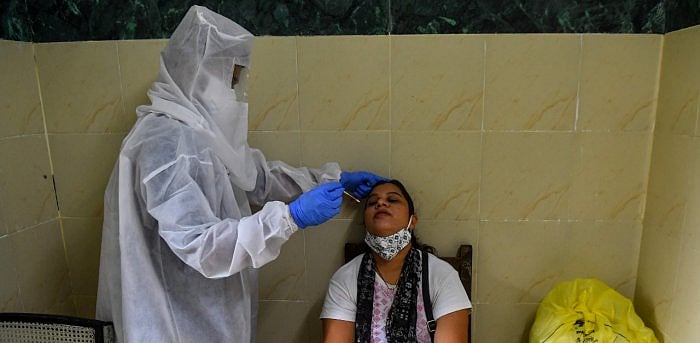 A health worker (L) takes a swab sample from a woman for a Covid-19 test. Credit: AFP Photo
