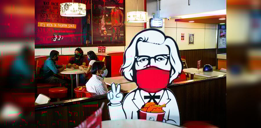 People wearing facemasks as a preventive measure against the Covid-19 coronavirus wait for their food in a Kentucky Fried Chicken (KFC) in New Delhi on October 16, 2020. Credit: AFP Photo