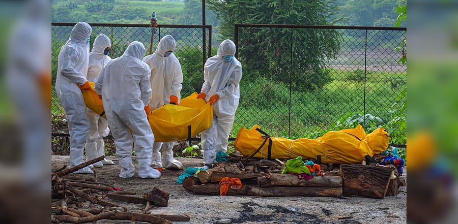 Relatives and health workers wearing PPE kits carry the bodies of persons who died of Covid-19 for cremation, at a crematorium in Karad. Credit: PTI File Photo