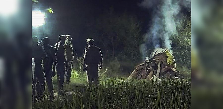 Police personnel cremate the body of a 19-year-old Dalit woman who was brutally gang-raped two weeks ago, in the wee hours, in Hathras district, Wednesday, Sept. 30, 2020.  Credit: PTI Photo