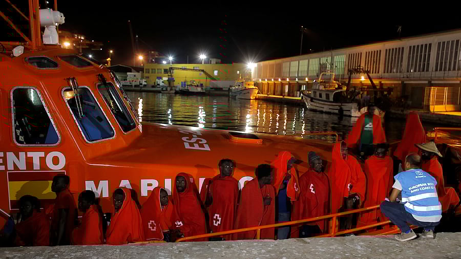 A member of Frontex talks to migrants as they wait to disembark from a rescue boat at the port of Malaga. Credits: Reuters Photo