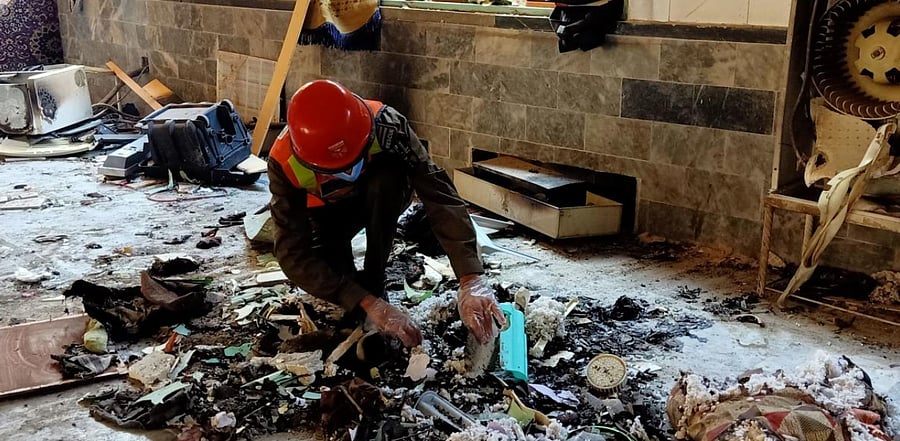 A rescue worker examines remains at the site of a blast at a religious school in Peshawar. Credit: AFP Photo