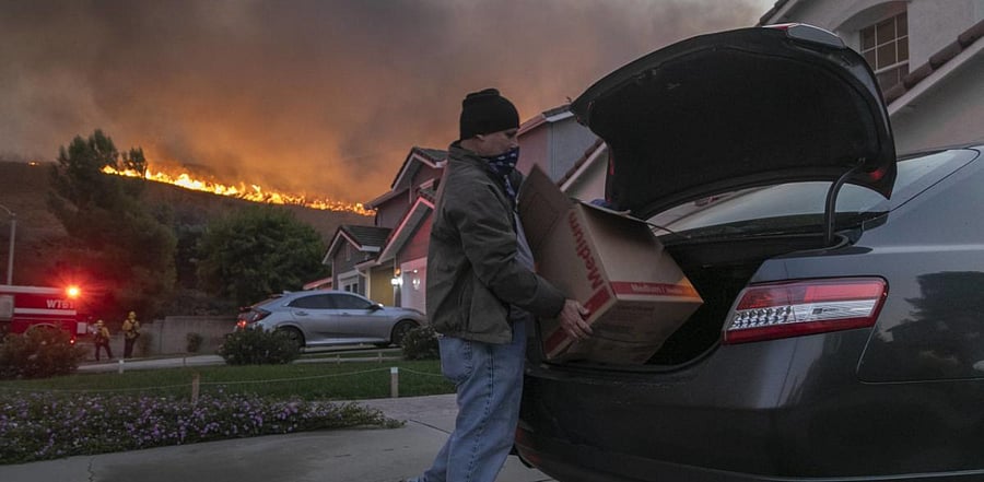 A man evacuates as flames come close to houses during the Blue Ridge Fire in Chino Hills, California. Credit: AFP Photo