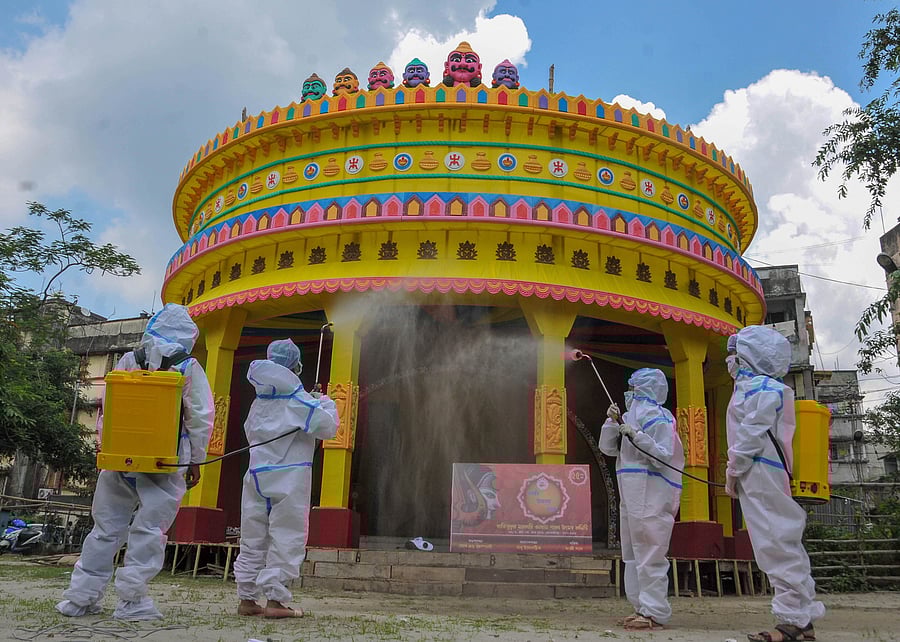 Members of community Durga Puja wearing PPE kit sanitize a puja pandal in the wake of coronavirus pandemic, ahead of the festival, in Kolkata. Credit: PTI Photo
