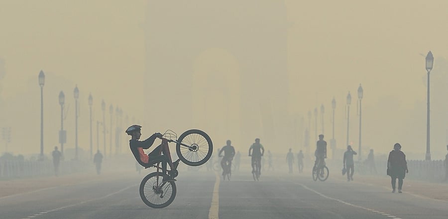 A cyclist performs stunts, during cold morning, amid hazy weather conditions, at Rajpath in New Delhi. Credit: PTI Photo