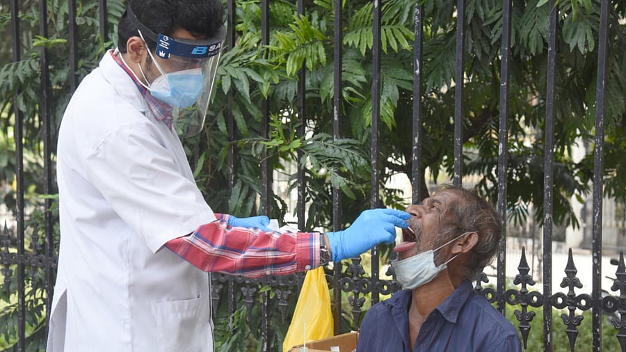 A healthcare worker takes the nasal swab of a man at a testing unit set up in front of the BBMP head office in Bengaluru on Sunday. Credits: DH Photo