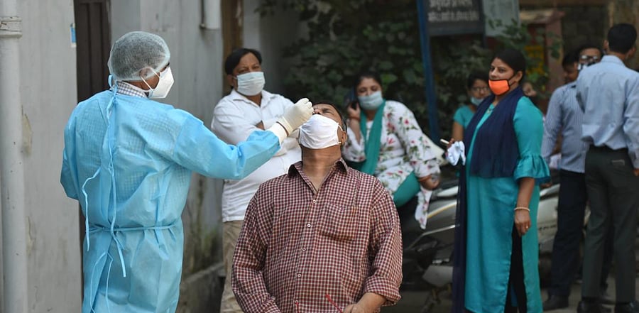 A health worker collects a sample from a man for Covid-19 test, at a dispensary in New Delhi. Credit: PTI Photo