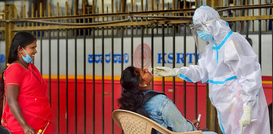A health worker wearing PPE kit collects samples for Covid-19 tests, at market in Bengaluru. Credit: PTI Photo