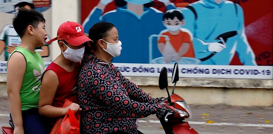 A woman wears a protective mask as she drives past a banner promoting prevention against the coronavirus disease in Hanoi, Vietnam. Credit: Reuters Photo