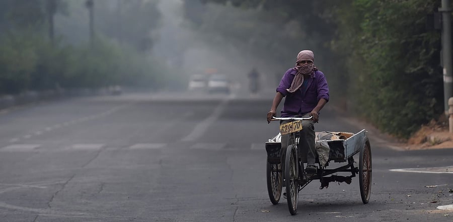 A worker pedals his tri-cycle cart amid an atmosphere shrouded in smog, in New Delhi. Credit: PTI Photo