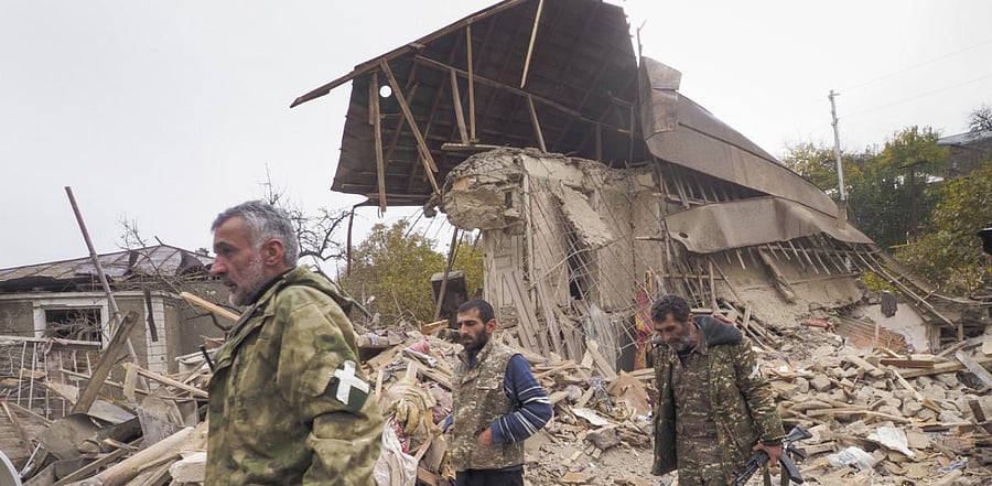 Ethnic Armenian soldiers walk past a house destroyed by shelling by Azerbaijan's artillery in Stepanakert, the separatist region of Nagorno-Karabakh. Credit: AP Photo