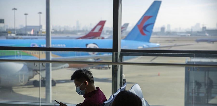 Travelers wearing face masks to protect against the coronavirus sit at a boarding gate. Credit: AP