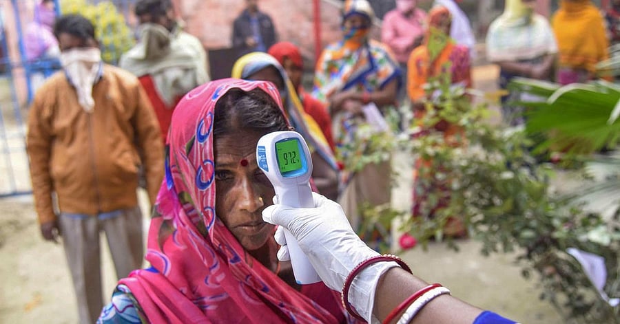 A voter undergoes thermal screening before casting vote during the third phase of Bihar Assembly Elections, at a polling station at Mahua in Vaishali on November 7, 2020. (PTI Photo)