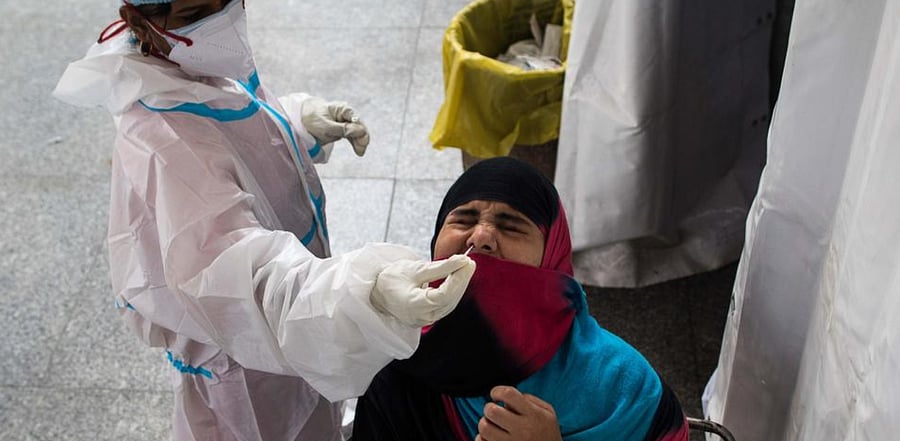 A medical worker collects a swab sample for a Rapid Antigen Test (RAT) for the Covid-19 coronavirus from a passenger before boarding a train at Hazrat Nizamuddin Railway Station in New Delhi on November 10, 2020. Credit: AFP Photo