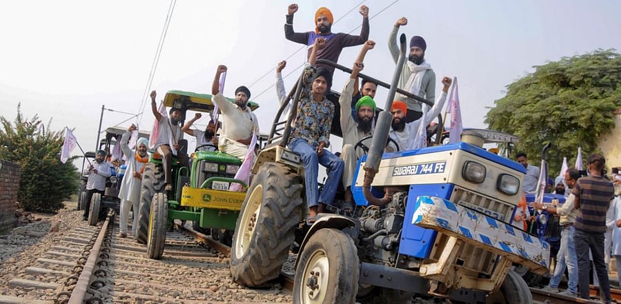 Farmers raise slogans as they block train tracks with tractors during the 'Rail Roko' protests. Credit: PTI