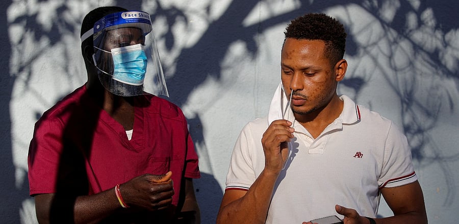 A healthcare worker stands by as a man takes a test for the coronavirus disease. Credit: Reuters Photo