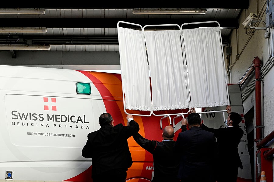 Private security personnel cover the ambulance transporting Argentine former football star and coach of Gimnasia y Esgrima La Plata Diego Maradona, as he leaves the clinic. Credits: AFP Photo