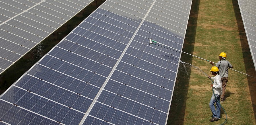 Workers clean photovoltaic panels inside a solar power plant in Gujarat. Representative Photo. Credit: Reuters