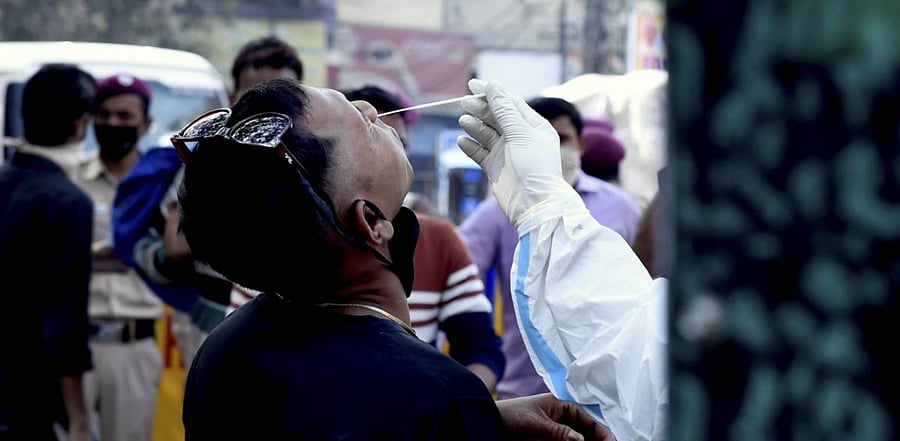 A health worker conducts Covid-19 testing at Baratooti Bazar, as coronavirus cases surge across New Delhi. Credit: PTI Photo