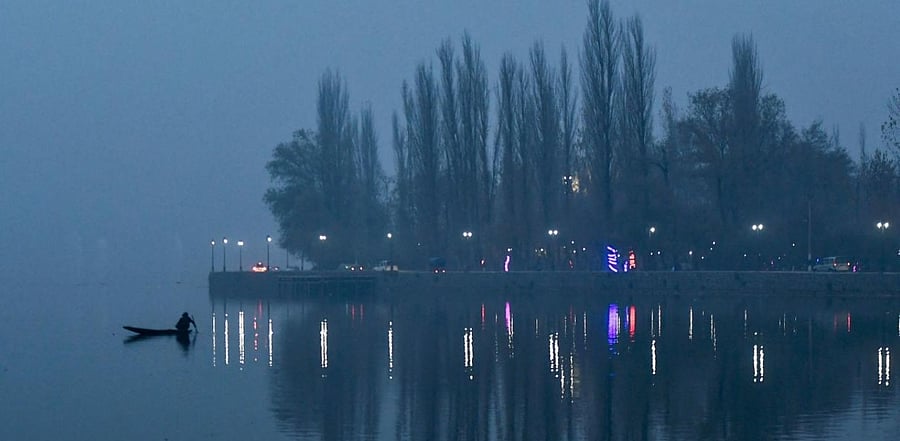 A person rows a boat amid dense fog in the Dal Lake in Srinagar on November 13, 2020. Credit: AFP Photo