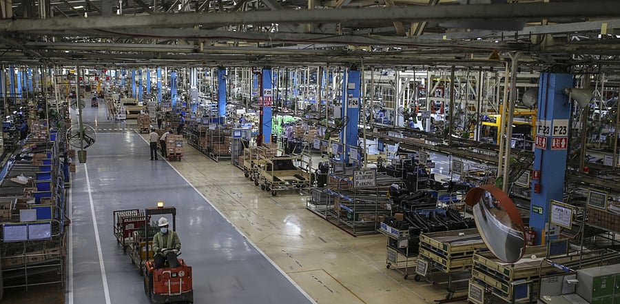 A workers drives a tug through the Innova Crysta compact multi-purpose vehicle (MPV) production line at the Toyota Kirloskar Motor Ltd. plant in Bidadi, Karnataka. Credit: Bloomberg file photo