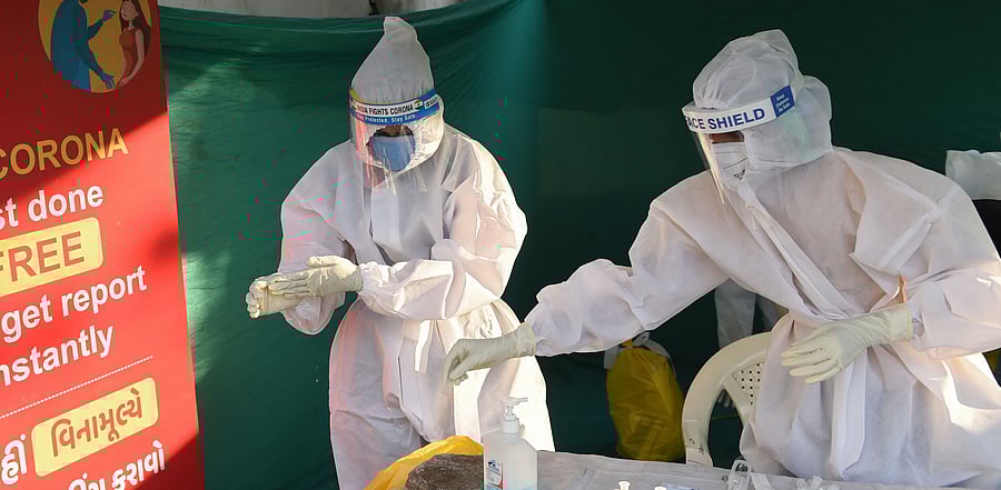 Health workers prepare to take swab sample from residents to test for the Covid-19 coronavirus outside Vastrapur Lake in Ahmedabad. Credit: AFP Photo