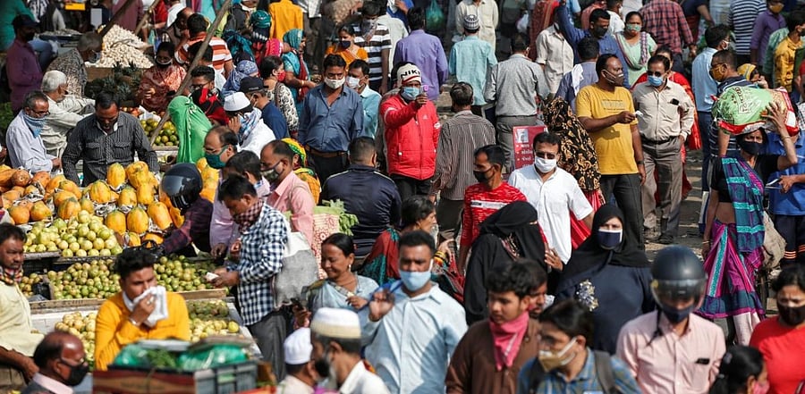 A health worker takes the temperature of shoppers at a crowded market amid the spread of the coronavirus disease in Ahmedabad. Credit: Reuters Photo