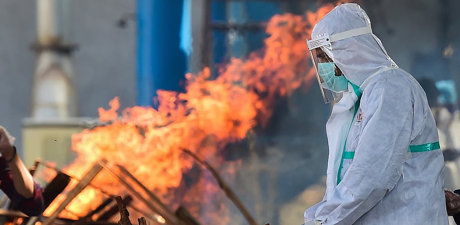 A relative wearing PPE performs last rites of a family member, who succumbed to COVID-19, at Nigambodh Ghat in New Delhi. Credit: PTI