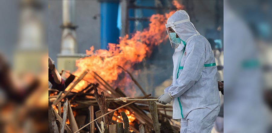 A relative wearing PPE performs last rites of a family member, who succumbed to Covid-19, at Nigambodh Ghat in New Delhi, Sunday, Nov 22, 2020. Credit: PTI Photo