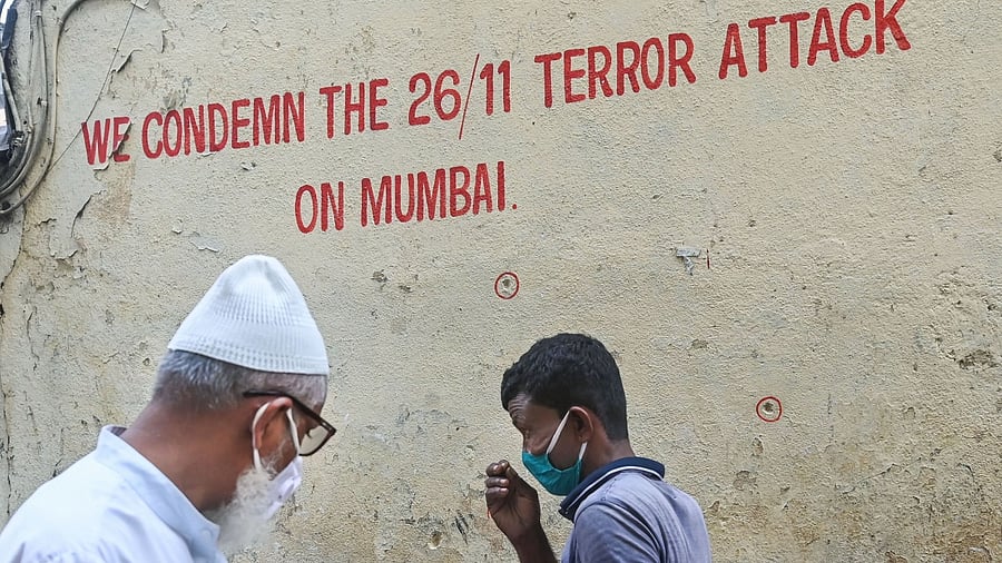 Pedestrians walk past bullet holes marked outside Nariman House, one of the sites of the 2008 Mumbai terror attacks that had claimed 166 lives, on the eve of the 26/11 terror attack's 12th anniversary. Credit: PTI Photo
