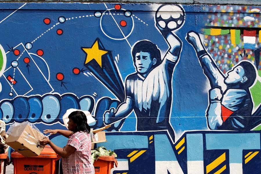 A resident stands near a mural depicting the famous "Hand of God" goal by former Argentine soccer star Diego Maradona. Credit: Reuters