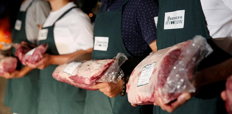 Employees of Shanghai All Food Win Co., Ltd. pose with beef at a storage area near the Pudong International Airport in Shanghai, China June 28, 2017. Credit: Reuters Photo
