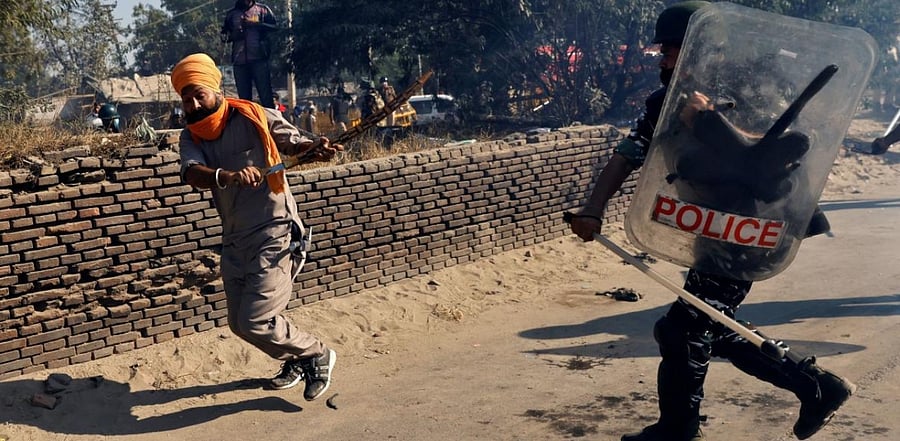 A policeman chases away a farmer during a protest against the newly passed farm bills at Singhu border near Delhi. Credit: Reuters.