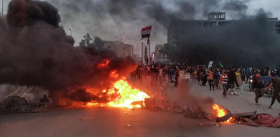 Smoke billows from burning tyres amid clashes between Iraqi anti-government protesters and supporters of firebrand Shiite cleric Moqtada Sadr, in the southern city of Nasiriyah. Credit: AFP Photo