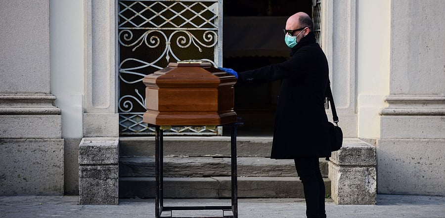 A man touches the coffin of his mother during a funeral service in the closed cemetery of Seriate, near Bergamo, Lombardy. Credit: AFP