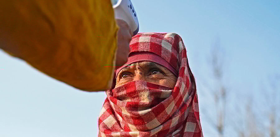 A health worker checks the body temperature of a voter as a preventive measure against the Covid-19 coronavirus during the first phase of the District Development Council (DDC) and Panchayat by-elections at a polling station in Shamsabad area of Budgam district. Credit: AFP