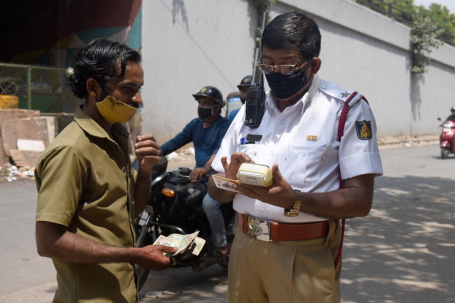 A traffic policeman fines a vehicle user for a traffic violation on NR Road, Bengaluru. DH PHOTO/S K DINESH