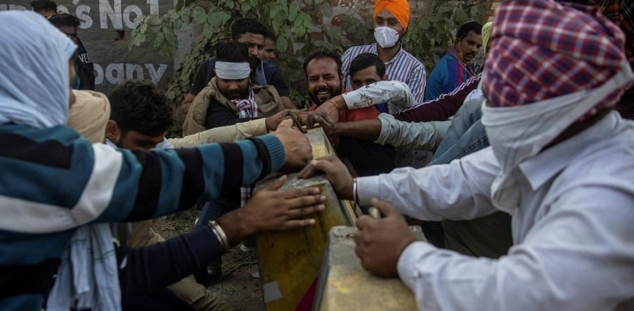 Farmers remove police barricades to reach to a protest site during a nationwide strike against the newly passed farm bills at Singhu border near Delhi. Credit: Reuters photo.