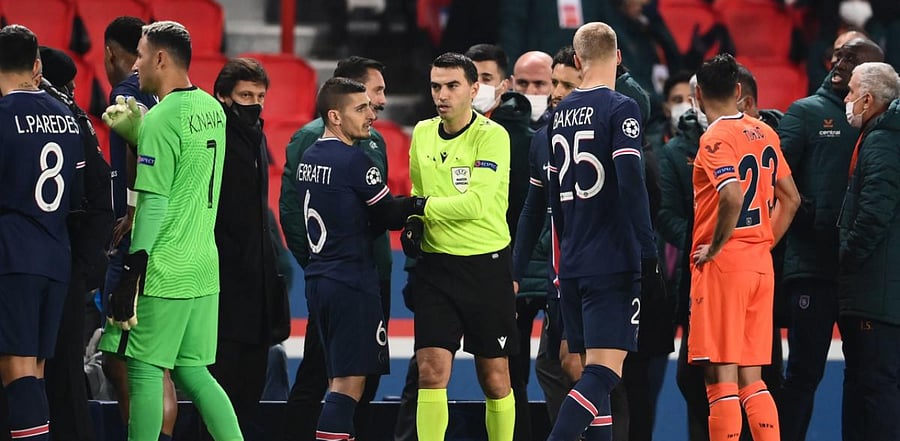 Romanian referee Ovidiu Hategan (in yellow) passes by Paris Saint-Germain's Italian midfielder Marco Verratti (CL) after the game was suspended amid allegations of racism by one of the match officials during the UEFA Champions League match. Credit: AFP Photo