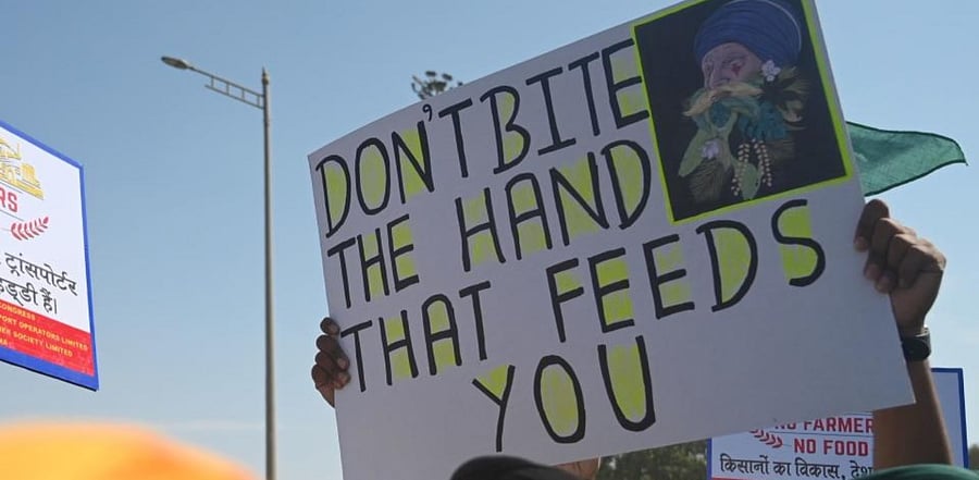 A protester holding a poster stands in front of policemen while blocking a highway during a nationwide general strike called by farmers to protest against the recent agricultural reforms in Mumbai on December 8, 2020. Credit: AFP Photo